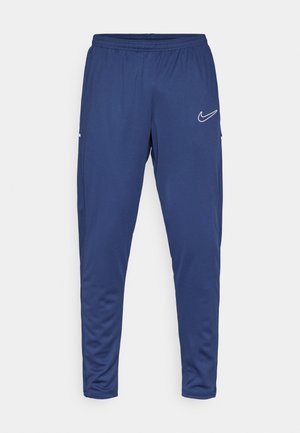 Navy blue athletic pants with elastic waistband, tapered design, and Nike swoosh logo in white on the left thigh. Soft, smooth texture.