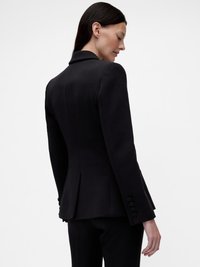 Blazer noir sur mesure avec manches longues, col à revers cranté et détails à boutons. Présente une silhouette ajustée et une texture lisse.