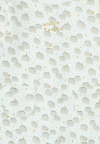 Tela blanca con patrones de nubes gris claro, pequeñas lunas crecientes naranjas y estrellas, y texto "totalmente mágico" en color naranja, dos bolsillos en la parte inferior.