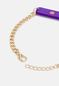 Acessório roxo com uma corrente dourada, apresentando um fecho de lagosta dourado e um pequeno detalhe de estrela rosa na parte roxa.