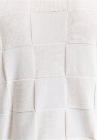 Tissu blanc en tricot avec un motif patchwork alternant des carrés en jersey endroit et en point mousse.