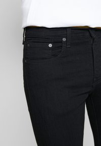 Svarta denimjeans med slim fit, med en klassisk femfickdesign och diskreta sömnadsdetaljer. Slät textur, standard dragkedja och knappstängning.