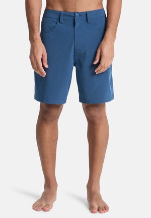 Blauwe katoenen shorts met knoopsluiting, ceintuurlussen en voorzakken, met een rechte zoom die net boven de knie valt.