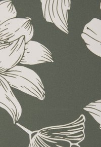 Gemusterter Stoff mit großen weißen Blumendesigns auf einem dunklen grünen Hintergrund, mit detaillierten Linienarbeiten auf Blütenblättern und Blättern.