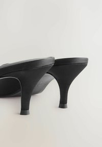 Schwarze High Heels haben ein glattes Obermaterial und einen schmal zulaufenden Absatz. Das Design ist minimalistisch mit einer strukturierten Form und mattem Finish.