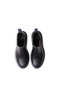 Pareja de botas negras sin cordones con punteras redondas y lengüetas en la parte posterior, vistas desde arriba sobre un fondo blanco.