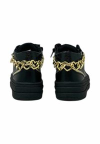 Sneaker neri con finitura testurizzata, con un accento a catena a forma di cuore dorato sul retro e una suola nera spessa.