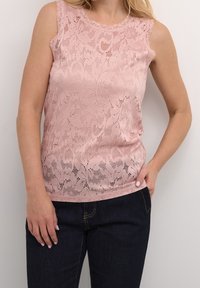 Růžový krajkový top bez rukávů s květinovými vzory, s pestrým výstřihem a volným střihem; v kombinaci s tmavými denimovými džíny.
