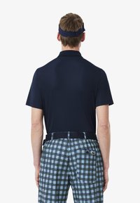 Marinblå pikétröja i kombination med rutiga shorts i blått, svart och grönt. Shortsen har en bakficka och elastisk midja.