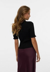 Černý ribbed top s krátkým rukávem a vlnitými okraji, přiléhavý střih, nošený s tmavě burgundy saténovou sukní, hladká textura a minimalistický design.