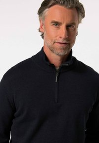 Suéter de cuello con cremallera en navy oscuro, con un borde acanalado y una tela suave y texturizada. Presenta una cremallera parcial en el cuello para ajustar.