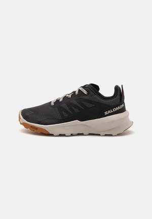 Black running shoe with a mesh upper, featuring silver laces, a cushioned white midsole, and a textured brown rubber outsole.