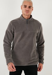 Grå fleece pullover med halv lynlås og høj krave. Har en glat tekstur og lange ærmer. Minimalistisk design uden mønstre eller accenter.