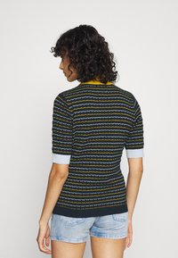 Stickad tröja med korta ärmar, prydd med navy, gul och ljusblåa ränder. Texturerat tyg med ribbad krage och mudd.