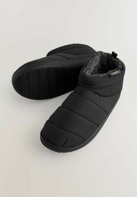 Papuci negri cu umplutură, căptușiți cu fleece gri texturat și tălpi din cauciuc. Design închis, cu degete rotunde și înălțime până la glezne pentru acoperire.