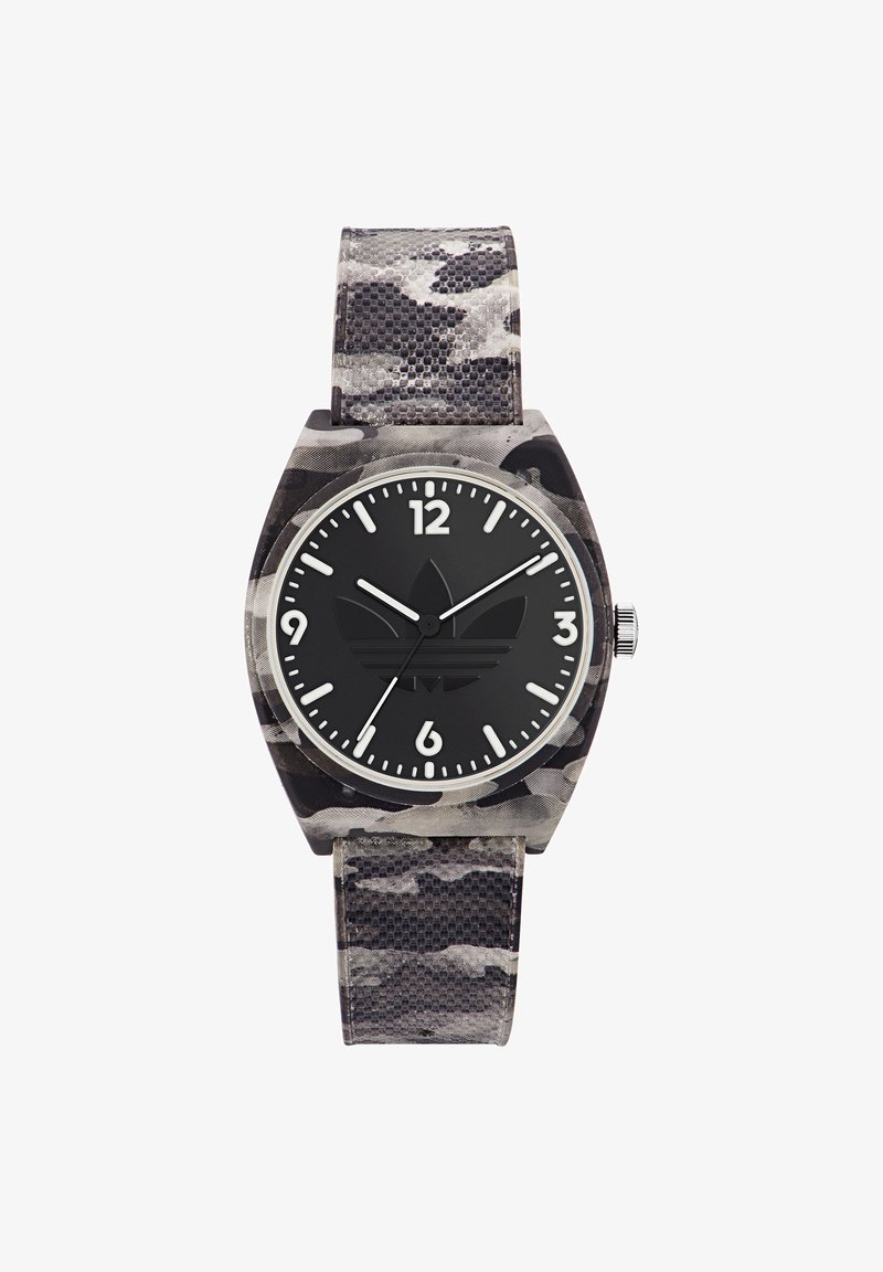Ceas cu camuflaj negru, cu o curea texturată, accesorii argintii și un cadran rotund negru care prezintă marcaje albe pentru ore și un logo în centru.