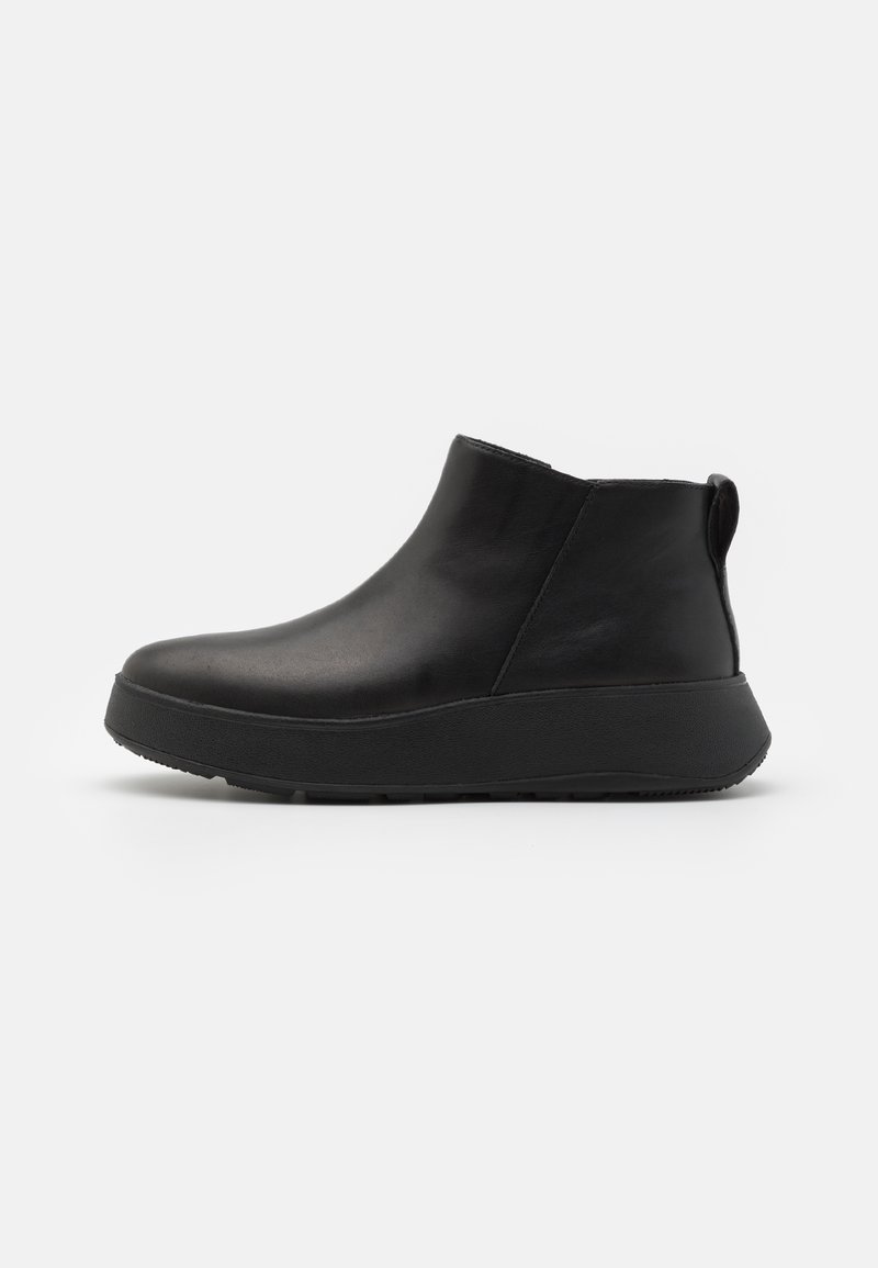 Sorte skinnankelsko med rund tå, hevet gummisåle og bakre pull-tab for enkel påkledning. Glatt tekstur og minimalistisk design.