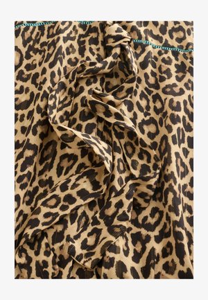 Textília s leopardím vzorom, s detailom viazaného uzla a tenkým zlatým vertikálnym prešitím, s tyrkysovým šitým lemom na hornom okraji.