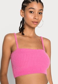 Top cropped rosa feito de material de malha felpuda, com textura canelada, alças finas e decote reto.