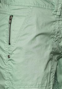 Un short cargo vert clair doté d'une poche zippée, de détails cousus et d'un tissu texturé. Idéal pour un usage décontracté et les activités de plein air.