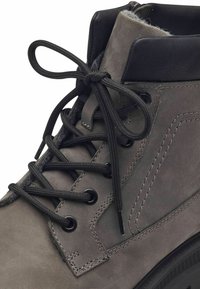 Bottines en cuir gris avec des accents noirs, lacets ronds noirs, col rembourré et coutures détaillées sur l'empeigne. Semelle en caoutchouc épaisse incluse.