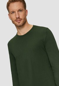 Langsleeve shirt in donkergroen katoen, voorzien van een ronde halslijn en een soepele textuur. De pasvorm is ontspannen zonder zichtbare patronen of accenten.