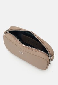 Borsa a tracolla beige testurizzata con zip superiore, hardware argentato e interno scuro con un'etichetta del brand ben visibile.