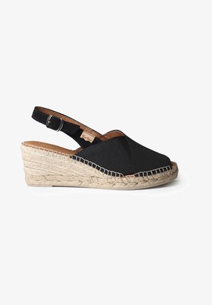 Sandale compensée en tissu noir avec semelle en jute tressé et bride réglable à la cheville avec boucle argentée, vue de côté sur fond blanc.