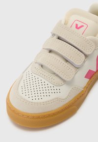 Beige sneakers med rosa detaljer, borrelås, perforert tå, laget av semsket skinn og lær, samt en såle i gummirubber. Lavprofil design.