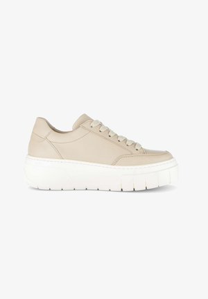 Beige lage sneaker met dikke witte platformzool en bijpassende beige veters, zijaanzicht op witte achtergrond.