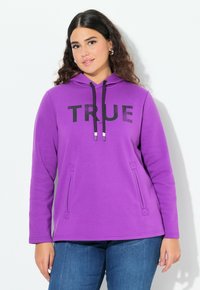 Sudadera morada con texto negro "TRUE", capucha con cordones y bolsillos laterales. Confeccionada en un tejido texturizado, presenta mangas largas y un corte relajado.