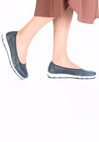 Dark blue slip-on shoes made of perforated leather, featuring a white sole with textured grip, designed for comfort and breathability.