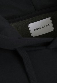 Zwarte hoodie met een zachte textuur, voorzien van een trekkoord en een label met "JACK & JONES" in het wit op een rechthoekig label.