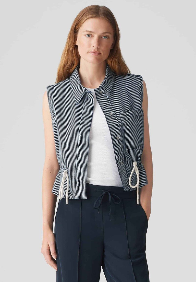 Gilet senza maniche a righe in blu navy e bianco, con colletto, bottoni frontali, taschino sul petto e lati regolabili con lacci per una vestibilità ottimale.