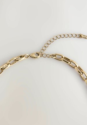 Aukso spalvos metalinė grandinėlė su ovaliais žiedais, su krabų užsegimu ir reguliuojama grandinėlės ilgio galimybe pritaikyti pagal pageidavimus. Lygi tekstūra.