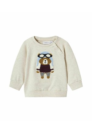 Sweatshirt beige clair avec un design de pilote d'ours, portant une casquette bleue et des lunettes. Poignets et ourlet inférieur côtelés, détails de broderie texturée.