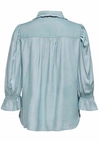 Blouse bleu clair vue de dos avec manches longues bouffantes, poignets froncés et col à volants.