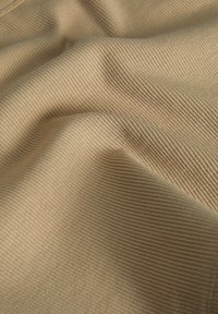Țesătură ribbed de un bej deschis, cu o textură moale, având caneluri ridicate și o cădere netedă, ideală pentru îmbrăcăminte sau tapițerie.