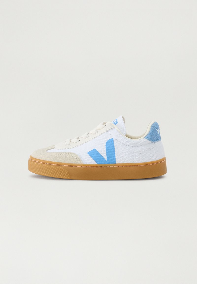 White sneaker with blue accents and tan sole, featuring a suede toe cap and a large "V" logo on the side. Laced design, minimalist style.