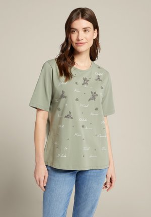 Hellgrünes Kurzarm-T-Shirt mit dekorativen Pailletten und gesticktem Text. Lockerer Schnitt mit runder Ausschnitt und weichem Baumwollstoff.