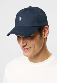 Șapcă de baseball bleumarin din bumbac, cu un mic logo alb brodat în față, cu bor curbat și cusături întărite.