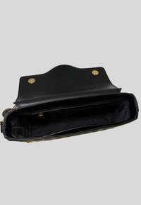Interno di una borsa a tracolla in pelle nera con una consistenza liscia, dotata di accessori in oro e due scomparti. Non foderata, con un design elegante.