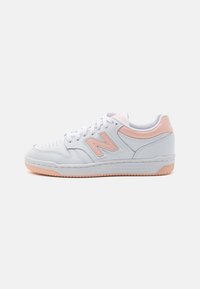 Baskets en cuir blanc avec des accents roses, bout perforé pour la respirabilité et une semelle en caoutchouc pour l'adhérence. Présente un logo 'N' bien en vue.
