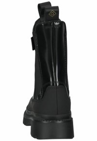 Bottines noires avec un mélange de matériaux brillants et mats, panneaux latéraux élastiques et une semelle en caoutchouc épaisse. Marquage sur le talon.