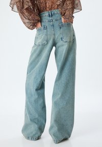 Hellblaue Marlene-Jeans aus Denim mit hoher Taille, zwei Gesäßtaschen und einer lockeren Passform mit einer verwaschenen Optik.