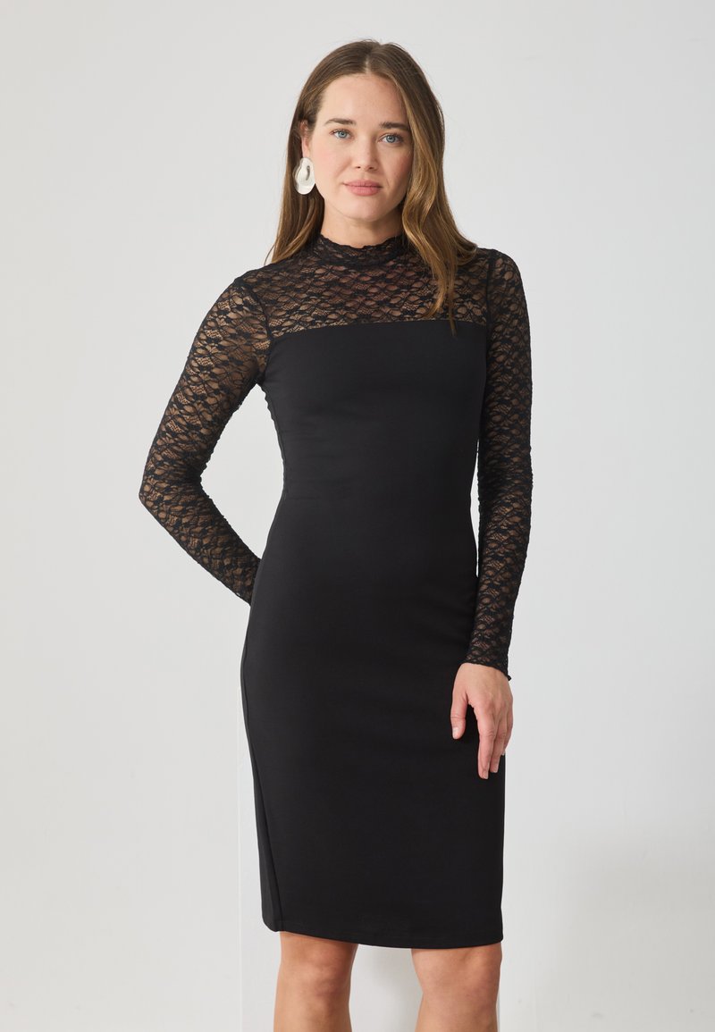 Rochie neagră, ajustată, cu mâneci lungi din dantelă, decolteu rotund și țesătură netedă. Dantela are un model floral. Fără accesorii sau elemente de metal vizibile.