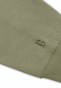 Olivgrüner Sweatshirtstoff mit einem strukturierten Strickmuster. Enthält ein gesticktes Logo am Ärmel und gerippte Bündchen.