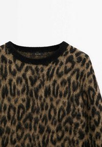 Pull à imprimé léopard avec une texture douce et duveteuse. Il présente un col rond noir et une base beige-brun. Étiquette visible à l'intérieur du col.