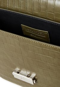 Torebka skórzana w kolorze oliwkowym z wzorem krokodylej skóry, z czarnym wnętrzem. Posiada zapięcie z srebrnym okuciem oraz metkę wewnątrz.