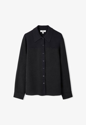 Černá košile s dlouhým rukávem a knoflíkovým zapínáním. Má kontrastní límec a oblast horního hrudníku s hladkou texturou a jemným leskem.